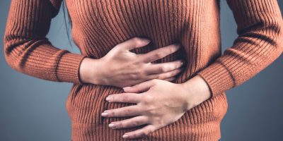 woman hand on ache stomach on dark background